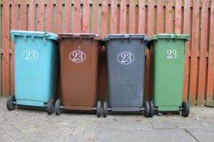Four wheeled trash cans lined up in a row for exterior cleaning.
