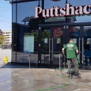 A man performing commercial cleaning on the exterior of a putschka store.