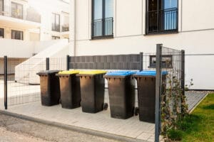 A group of trash cans in front of a building undergoing Exterior Cleaning.