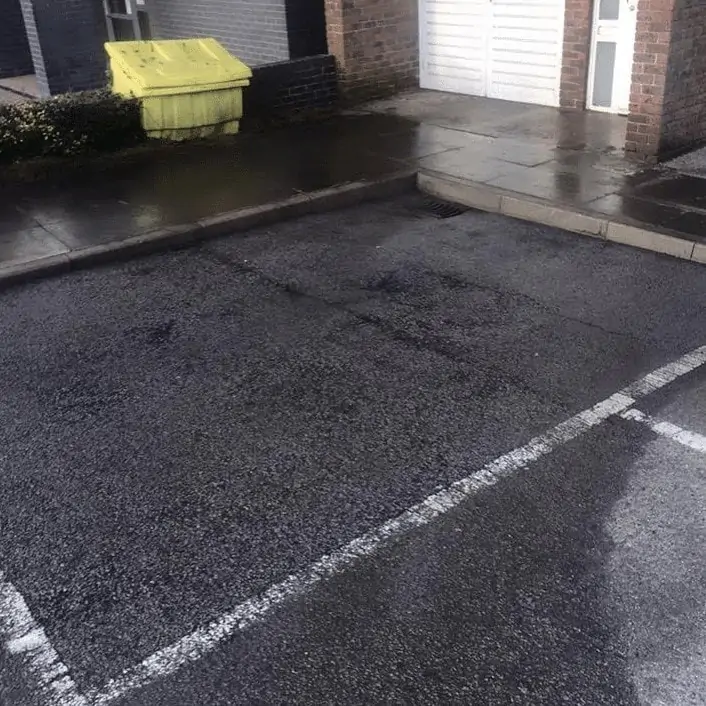 A parking lot with a white line on it, undergoing exterior cleaning.